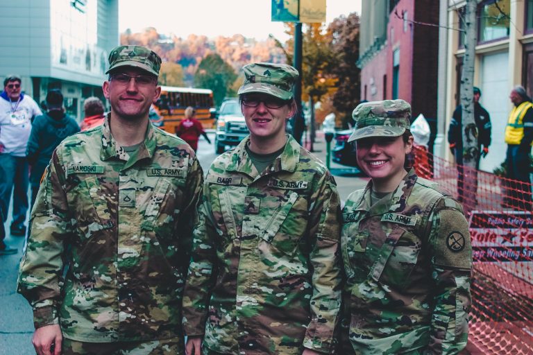 three soldiers in the army smiling for the camera